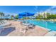 A resort-style pool area with lounge chairs, tables, umbrellas, and blue skies at 1065 Gulf Of Mexico Dr # 103, Longboat Key, FL 34228