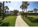 A paved walkway leads to a common pool area, with lush landscaping and palm trees at 1065 Gulf Of Mexico Dr # 103, Longboat Key, FL 34228