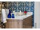 Bathroom vanity with double sinks, wood cabinets, and blue patterned wallpaper at 111 S Pineapple Ave # 716, Sarasota, FL 34236