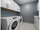 Laundry room with a washer, dryer, overhead cabinets, and contemporary patterned wallpaper at 111 S Pineapple Ave # 716, Sarasota, FL 34236
