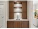 Elegant bar area boasts custom wooden cabinets, open shelving with glass racks, and a sleek beer tap at 12311 Newcastle Pl, Lakewood Ranch, FL 34202