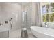 Bright bathroom featuring soaking tub, glass shower, and stylish fixtures near a large window at 12311 Newcastle Pl, Lakewood Ranch, FL 34202