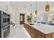 Modern kitchen with wood-grain island, white cabinets, and stainless appliances, seamlessly connecting living spaces at 12311 Newcastle Pl, Lakewood Ranch, FL 34202