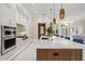 Gourmet kitchen showcasing sleek white cabinets, stainless steel appliances, an expansive island, and an open layout at 12311 Newcastle Pl, Lakewood Ranch, FL 34202