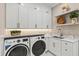 Well-lit laundry room featuring modern washer and dryer, white cabinetry, granite counters, and shelving with decor at 12311 Newcastle Pl, Lakewood Ranch, FL 34202