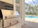 Stainless steel outdoor grill with black granite countertop overlooking brick patio and screened in pool at 12311 Newcastle Pl, Lakewood Ranch, FL 34202