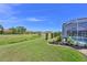 A backyard view featuring green grass, landscaping, pool, and screened-in patio in the background at 12811 Penguin Dr, Bradenton, FL 34212