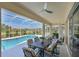 An inviting screened-in patio featuring a dining set and ceiling fan, overlooking the pool and landscaped yard at 12811 Penguin Dr, Bradenton, FL 34212