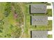 Aerial view shows backyard with lush grass and fence, between other homes and natural wooded space at 16109 6Th E Ave, Bradenton, FL 34212
