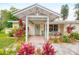 Inviting front entrance with covered porch, pastel door, brick walkway, and mature tropical landscaping at 1731 Redwood St, Sarasota, FL 34231