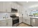 Stylish kitchen showcasing stainless steel appliances, a farmhouse sink, and a seamless connection to living area at 17885 Cherished Loop, Bradenton, FL 34211