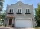 Two-story gray home with a garage, arched wood door, paver driveway and black flower boxes on the second story at 2221 Bahia Vista St, Sarasota, FL 34239