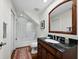 Traditional bathroom with wood vanity, stone countertop, shower/tub and decorative mirror at 2282 Harbour Court Dr, Longboat Key, FL 34228