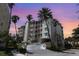 Exterior of a multi-story condo building featuring palm trees and beautiful sunset sky at 242 Hidden Bay Dr # 603, Osprey, FL 34229