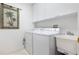 A laundry room features white cabinets and a laundry sink with modern washer and dryer units at 242 Hidden Bay Dr # 603, Osprey, FL 34229