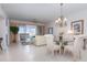 Bright living room with tile floors, dining area, chandelier, and sliding glass doors to a balcony at 242 Hidden Bay Dr # 603, Osprey, FL 34229