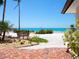 Coastal backyard oasis with a cozy bench, lush tropical plants, a brick patio and turquoise ocean views at 3300 Casey Key Rd, Nokomis, FL 34275