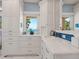Bathroom with white cabinets, marble countertops, blue tile backsplash, and a window view at 3300 Casey Key Rd, Nokomis, FL 34275
