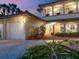 Well-lit home with a 2-car garage, brick walkway, manicured greenery, and an arched front door at 3300 Casey Key Rd, Nokomis, FL 34275