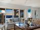 Bright living room with a blue sofa, glass coffee table, and large sliding glass doors with ocean views at 3300 Casey Key Rd, Nokomis, FL 34275