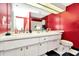 Bathroom showcasing a dual sink vanity with white cabinets and bold red walls, accented by black and white tile floors at 36750 Us 19 N # 03102, Palm Harbor, FL 34684