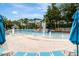 Resort-style pool area featuring a sandy beach entrance, rock features, and multiple lounge chairs under blue umbrellas at 36750 Us 19 N # 03102, Palm Harbor, FL 34684
