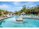 Community pool area with waterfalls, seating, umbrellas, and mature trees under a partly cloudy sky at 36750 Us 19 N # 03102, Palm Harbor, FL 34684