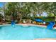 Community pool with blue slides, steps, lush landscaping and mature trees creating a fun outdoor recreational space at 36750 Us 19 N # 03102, Palm Harbor, FL 34684