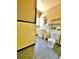 Bathroom with unique yellow wall and green floor tile; single sink and shelving at 4221 26Th W St, Bradenton, FL 34205