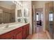 Bathroom with a walk-in shower, wooden vanity, double mirror, and adjacent bedroom at 4706 Josselin Pl, Parrish, FL 34219