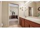 Bright bathroom with a wooden vanity, light tile flooring, and a decorative mirror at 4706 Josselin Pl, Parrish, FL 34219