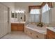 Well-lit bathroom with tiled tub surround, wooden vanity, and a sunlit window at 4706 Josselin Pl, Parrish, FL 34219
