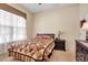 Comfortable bedroom featuring a decorative quilt, window with blinds, and a dark wood nightstand at 4706 Josselin Pl, Parrish, FL 34219