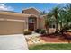 Charming home exterior with a two-car garage, manicured lawn, and tropical landscaping creating a welcoming curb appeal at 4706 Josselin Pl, Parrish, FL 34219