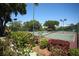 Well-maintained tennis courts with green fencing, lighting, and beautiful landscaping in a serene setting at 5106 Far Oak Cir, Sarasota, FL 34238