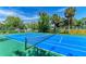 Bright blue and green community tennis court surrounded by lush greenery and palm trees under a sunny sky at 5400 26Th W St # F104, Bradenton, FL 34207