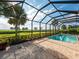 Screened pool enclosure with clear blue pool water, brick patio, and serene views of the lush greenery and waterway beyond at 5402 Tidewater Preserve Blvd, Bradenton, FL 34208