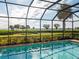 Screened pool area with a brick patio, clear blue swimming pool, palm trees and lush greenery beyond at 5402 Tidewater Preserve Blvd, Bradenton, FL 34208
