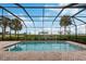 Backyard pool inside screened-in enclosure; views of manicured landscaping and water in the distance at 5402 Tidewater Preserve Blvd, Bradenton, FL 34208