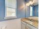A lovely bathroom featuring a granite countertop, white cabinets, blue walls, and natural light at 6125 35Th E Ct, Bradenton, FL 34203