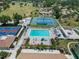 Aerial view showcasing the community pool, tennis courts, pickleball and shuffleboard courts, and well-maintained landscaping at 672 White Pine Tree Rd # 57, Venice, FL 34285