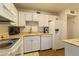 A clean, galley kitchen featuring white appliances, cabinets, and countertops in a compact space at 672 White Pine Tree Rd # 57, Venice, FL 34285