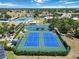 Aerial view of well-maintained blue tennis courts surrounded by lush landscaping, offering a premium sports amenity at 672 White Pine Tree Rd # 57, Venice, FL 34285