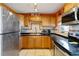 Traditional-style kitchen with wood cabinetry, black countertops, stainless steel appliances, and tile backsplash at 6720 Northampton Pl, Bradenton, FL 34207