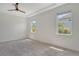 Bright, spacious bedroom with neutral carpet, tray ceiling, and natural light from dual windows at 6800 Dunlin Ct, Sarasota, FL 34241