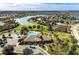 Scenic aerial view of community pool, clubhouse, and shimmering lake amidst lush landscaping, showcasing upscale amenities at 7822 110Th E Ave, Parrish, FL 34219