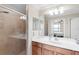 Bathroom with tiled shower and wood vanity, featuring a white countertop, and a large mirror with decorative lighting at 8205 Grand Estuary Trl # 101, Bradenton, FL 34212