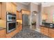 Kitchen featuring stainless steel refrigerator, double oven, granite countertops, and wood cabinetry at 8838 Bloomfield Blvd, Sarasota, FL 34238