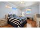 Comfortable bedroom featuring a blue striped bedspread, ceiling fan, and plenty of natural light at 8995 Founders Cir, Palmetto, FL 34221