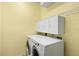 This laundry room is efficiently designed with overhead cabinets and modern, front-loading washer and dryer units at 8995 Founders Cir, Palmetto, FL 34221